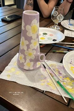 a woman sitting at a table with paint and paper