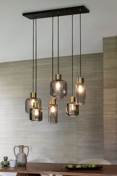 a dining room table and chairs with lights hanging from the ceiling