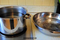 two stainless steel pans sitting on top of a stove next to a bowl with boiling water in it