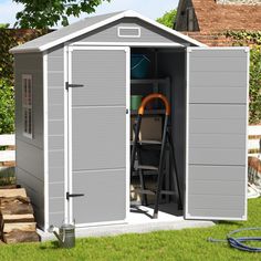 a gray shed sitting on top of a lush green field