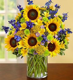 a bouquet of sunflowers and bluebells in a vase on a table