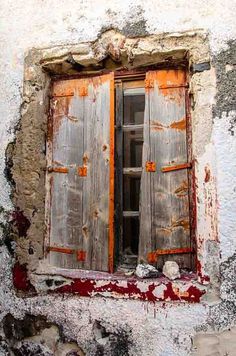 an old window with wooden shutters and peeling paint