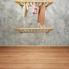 an empty room with wooden floors and clothes hanging on the rack in front of it