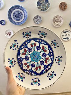 a hand is pointing at a plate with blue and red designs on it