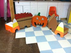 several cardboard pumpkins and chairs are on the floor in front of a kitchen counter