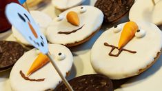 frosted cookies with icing and decorated like snowmen are arranged on a table