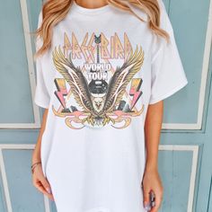 Embark on a retro music journey with the Free Bird World Tour Shirt. Featuring a vintage-inspired design with an eagle, this Comfort Colors Boho T-Shirt is perfect for music enthusiasts. All clothing and accessories from The Southern Thistle are handmade-to-order, just for you! ☺️  SIZING: Tshirts and sweatshirts are unisex, classic fit. Please refer to size chart in listing photos for details. Easy measuring tip: Take your favorite shirt, lay it on a flat surface and measure the width (armpit t Retro Crew Neck T-shirt For Music Festival, Retro Graphic Print Top For Concert, Retro Band Logo Tops For Music Festivals, Retro White Tops For Music Festivals, Graphic Tee With Front Print For Music Festival, White Sublimation Print Top For Music Festival, Music Festival Graphic Tee With Front Print, Band Logo Graphic Tee For Music Festival, Retro Graphic Print Top For Music Festivals