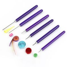 six different colored crochet hooks with thread and sewing needles next to each other