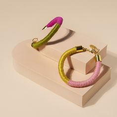 two pairs of pink and green hoop earrings on top of a white box with gold accents