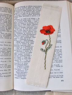 an open book with a cross stitch flower on it