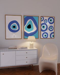 three paintings hang on the wall above a white dresser