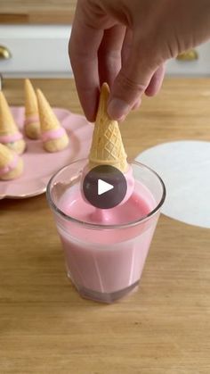 a person dipping some kind of ice cream into a glass with pink liquid in it