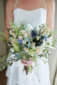 a bride holding a bouquet of flowers and greenery