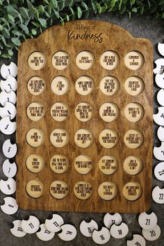 a wooden plaque with the names and dates of children's numbers on it, surrounded by green leaves