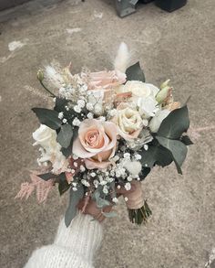 a bridal bouquet in someone's hand