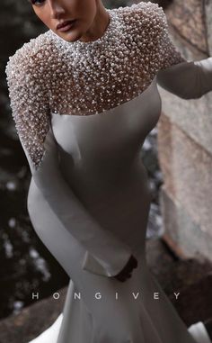 a woman in a white dress and pearls on her head is posing for the camera