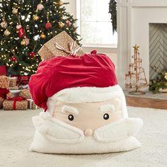 a santa claus pillow sitting on top of a white rug next to a christmas tree