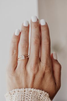 a woman's hand with white manicured nails and a gold ring