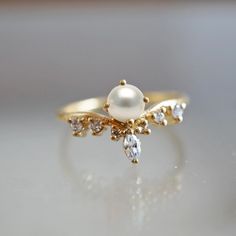 a pearl and diamond ring on a table