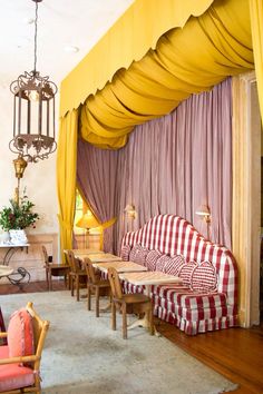 a living room filled with furniture under a yellow drape covered area next to a fire place