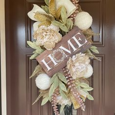 a front door wreath with flowers and a home sign