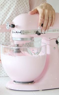 a woman is using a pink mixer to make something