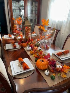 a dining room table set for thanksgiving with pumpkins and gourds on it