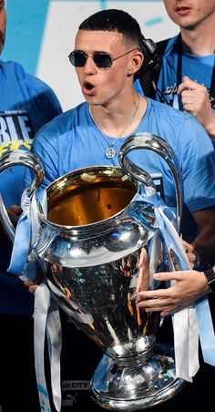 a man in sunglasses holding up a silver trophy