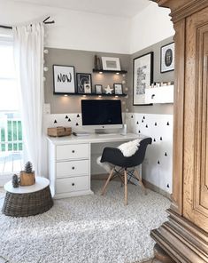 a white desk with a computer on top of it in a room filled with pictures