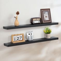 two black floating shelves with pictures and other items on them, along with an owl figurine