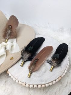 three hats with feathers on them sitting on top of a white fur covered tablecloth