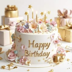 a birthday cake with flowers and candles on it, surrounded by gifts in gold foil