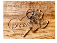 two heart shaped keychains with the words mom and daughter engraved on them, sitting on a wooden surface