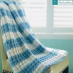 a blue and white striped blanket sitting on top of a chair next to a window