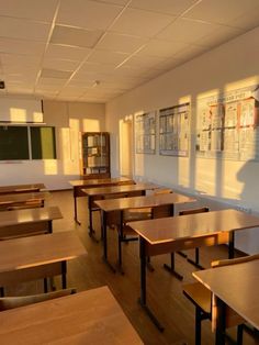 an empty classroom with wooden desks and posters on the wall