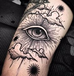 an all seeing eye tattoo on the left arm with stars and clouds around it in black ink