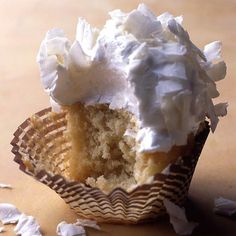 a half eaten cupcake with white frosting sitting on top of a wooden table