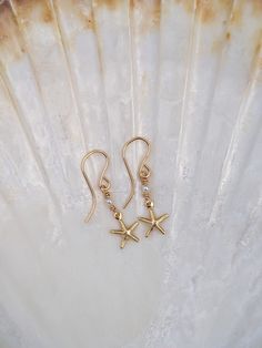 Starfish Earrings with a Shell Pearl.  - Made From: Gold Fill - Gemstone: Pearl - made from the inside of a pearl shell, so not a freshwater pearl nor mother of pearl but made from the shell itself  - Pendant Size: starfish - 1Omm. Pearl - 2mm, these are lightweight. As they are handmade please note pieces will never have the same finish as machine made/mass produced.  Each one is unique. What is Gold Fill  - Gold Filled Jewellery is a thick layer of Real solid 14k Gold bonded over a base Metal of sterling silver or brass.  - Gold Fill will not tarnish and will never reveal the base layer - it is hypoallergenic  - if looked after well Gold Fill jewellery pieces can last a life time.   - stamped with 14k - Affordable substitute to Real Gold  All my Gemstones are Ethically sourced and due to Ocean-inspired Pearl Drop Earrings As A Gift, Star-shaped Pearl Drop Earrings As Gift, Gold Starfish Jewelry With Pearl Charm, Star-shaped Pearl Drop Jewelry For Gifts, Star-shaped Pearl Drop Jewelry As Gift, Elegant Starfish Charm Drop Earrings, Elegant Starfish Charm Earrings For Gift, Elegant Starfish Charm Earrings As Gift, Star-shaped Pearl Jewelry For Gift