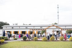 a large group of people standing in front of a white building with orange trimmings