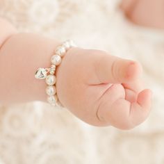 Close-up of a baby's tiny hand with a Baby Beau & Belle White Luster Pearl Bracelet with Silver Heart Charm, resting on a soft, textured blanket. Baby Heart, White Pearl Bracelet, Heirloom Gifts, Baby Jewelry, Flower Girl Gifts, First Birthday Gifts, Gifts Baby, Tin Gifts, Baby Newborn