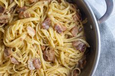 a pan filled with pasta and meats on top of a table next to a towel