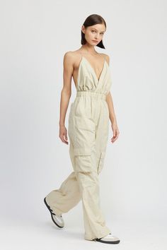 Introducing the perfect addition to your casual wardrobe: our Nixon Cargo Jumpsuit! With its V-neckline, elastic waist and loose, cargo pants, this jumpsuit is sure to become your new go-to. Model is 5’9” wearing a size small. Fabric Contents: 100% Nylon Spring V-neck Overalls With Pockets, Cargo Style Overall Jumpsuit For Summer, Beige Jumpsuits And Rompers With Elastic Waistband For Spring, Summer Utility Jumpsuits And Rompers, Trendy Cargo Style Jumpsuits And Rompers For Spring, Trendy Spring Cargo Style Jumpsuits And Rompers, Trendy Summer Overalls With Cargo Pockets, Solid Color Utility Jumpsuits And Rompers For Summer, Trendy Cargo Style Overall Jumpsuits And Rompers