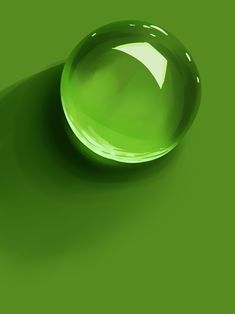 an image of a green glass ball on a green surface with the light reflecting off it's side