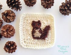 pine cones and crocheted teddy bears are arranged around a small square in the shape of a bear