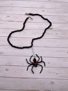 a black beaded necklace with a spider hanging from it's side on a wooden surface