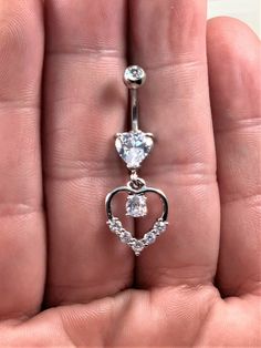 a person is holding a heart shaped belly ring in their left hand, with the top section