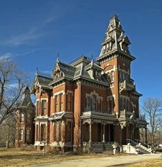 an old brick building with a steeple on the top and two stories, in front of a blue sky