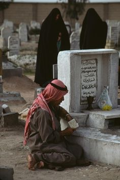 a man sitting on the ground next to a grave