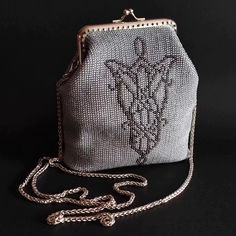 a silver purse sitting on top of a black table next to a white chain strap