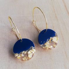 two blue and gold earrings sitting on top of a table